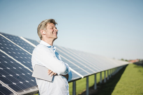 Geschäftsmann mit drahtlosem Kopfhörer und Tablet im Solarpark - MOEF01160