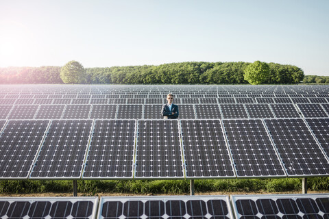 Älterer Mann steht auf einem Panel in einer Solaranlage, lizenzfreies Stockfoto