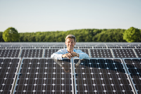 Smailing mature man standing in solar plant stock photo