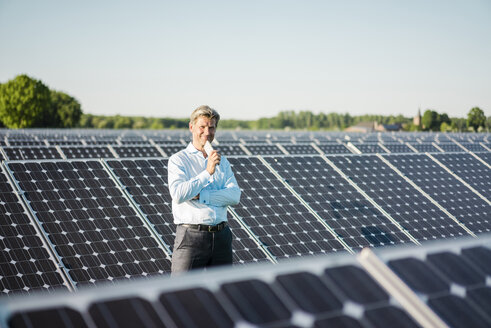 Älterer Mann mit Smartphone in Solaranlage stehend - MOEF01184