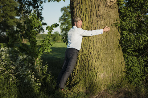 Mann umarmt Baum, lizenzfreies Stockfoto