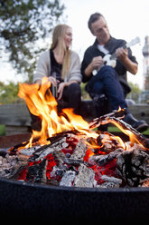 Flames in fire pit, couple in background - CUF13721