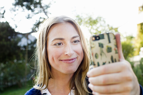 Mittlere erwachsene Frau hält Smartphone, lizenzfreies Stockfoto