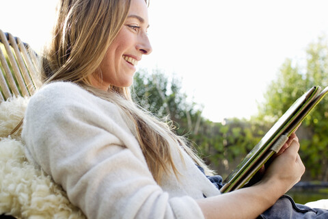 Porträt einer mittleren erwachsenen Frau, die ein digitales Tablet benutzt, lächelnd, lizenzfreies Stockfoto
