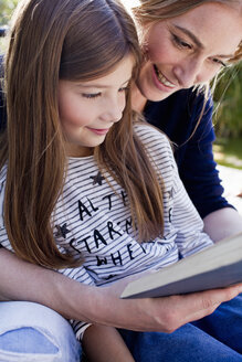 Mutter und Tochter lesen gemeinsam ein Buch, lächelnd - CUF13747