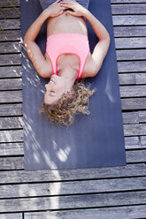 Young woman lying on yoga mat, high angle - CUF13755