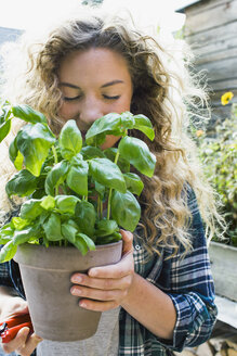 Young woman holding fresh basil in pot - CUF13781