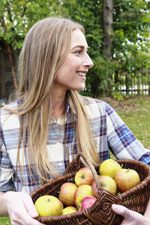 Mittlere erwachsene Frau mit Korb voller selbst angebauter Äpfel - CUF13783