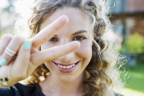 Young woman making peace sign with hand - CUF13812