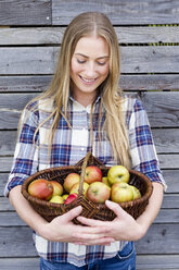 Mittlere erwachsene Frau mit Korb voller selbst angebauter Äpfel - CUF13821
