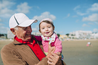 France, La Baule, portrait of baby girl on grandfather's arms on the beach - GEMF02018