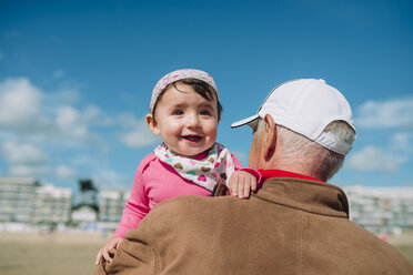 France, La Baule, portrait of baby girl on grandfather's arms on the beach - GEMF02019