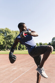 Junger afroamerikanischer Mann trainiert Boxen auf einem Sportplatz, im Freien - UUF13870