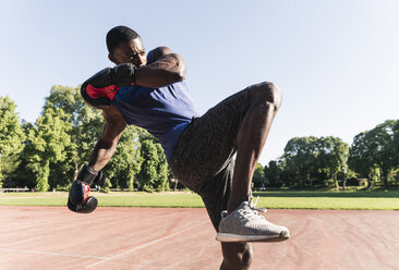 Junger afroamerikanischer Mann trainiert Boxen auf einem Sportplatz, im Freien - UUF13871