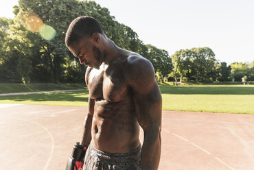 Young Afro-American man training boxing on sports field, outdoors - UUF13876