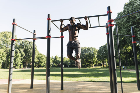 Muskulöser junger Mann beim Training auf einem Parcours mit Barren, lizenzfreies Stockfoto