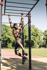 Muskulöser junger Mann beim Training auf einem Parcours mit Barren - UUF13881