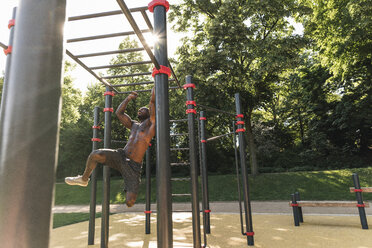 Muscular young man exercising on parcours bars - UUF13882