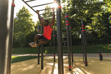 Muscular young man exercising on parcours bars - UUF13883