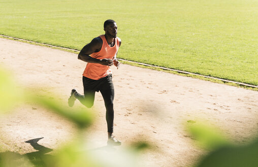 Junger Sportler auf dem Sportplatz beim Lauftraining - UUF13898