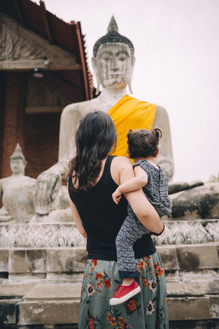 Thailand, Ayutthaya, Rückenansicht von Mutter und kleiner Tochter beim Besuch des Wat Yai Chaya Mongkhon, lizenzfreies Stockfoto