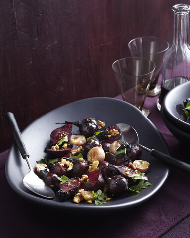 Schüssel mit warmem Rote-Bete-Salat auf dem Tisch mit Rotwein, lizenzfreies Stockfoto