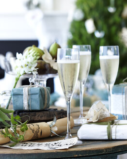 Nahaufnahme eines Tisches mit Champagner, Weihnachtsgebäck und Geschenken - CUF13866
