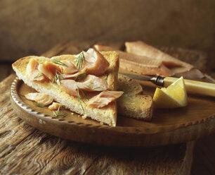 Lachs auf Toast mit Dill und Zitronenscheibe, auf einem Schneidebrett - CUF13908
