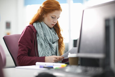 Junge Studentin am Computer Schreibtisch lesen Papierkram - CUF13990