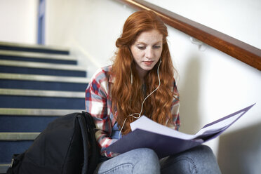 Young female college student sitting on stairway reading file - CUF14000