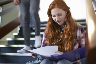 Young female college student sitting on stairway revising from file - CUF14001