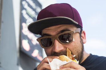 Male customer eating hamburger from fast food van - CUF14003
