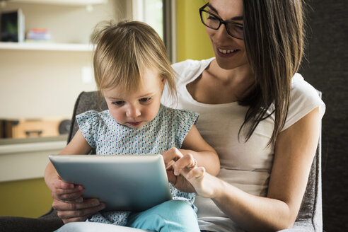 Mutter bringt ihrer Tochter den Umgang mit dem Tablet zu Hause bei - CUF14020