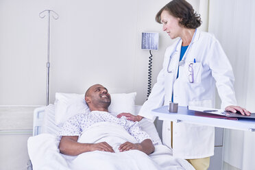 Arzt berät sich mit einem im Krankenhausbett liegenden Patienten - CUF14047