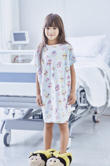 Portrait of girl patient wearing bumblebee slippers in hospital children's ward - CUF14059