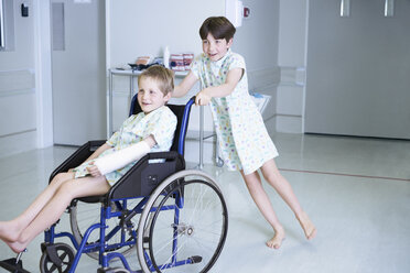 Junge Patienten schieben ihren Freund im Rollstuhl auf der Kinderstation eines Krankenhauses - CUF14071