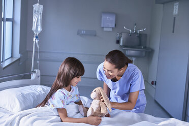 Krankenschwester und Patientenmädchen spielen mit Spielzeugkaninchen auf der Kinderstation eines Krankenhauses - CUF14080