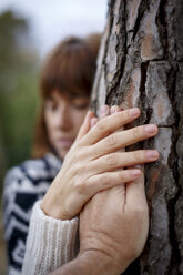 Woman holding mans hand hugging tree - CUF14120