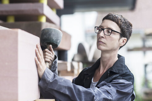 Stonemason using mallet checking block of stone - CUF14132