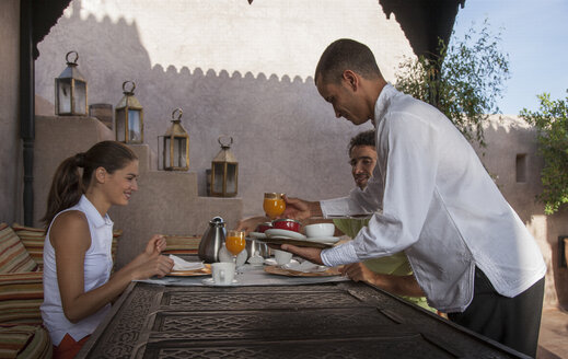 Kellner serviert jungem Paar Frühstück, Marrakesch, Marokko - CUF14154