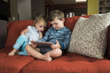 Geschwister benutzen digitales Tablet auf dem Sofa - CUF14162