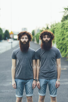 Porträt von eineiigen erwachsenen männlichen Zwillingen mit roten Haaren und Bärten auf dem Gehweg - CUF14213