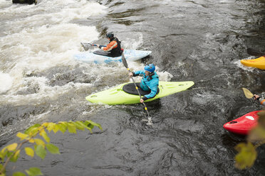 Kajakfahrer und Kajakfahrerin paddeln zu Stromschnellen auf dem Fluss Dee, Llangollen, Nordwales - CUF14219