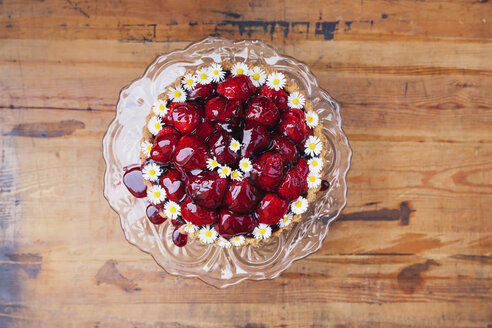 Hausgemachter Erdbeerkuchen mit roter Traubensaftglasur und Gänseblümchendekoration auf Glaskuchenständer - GWF05517