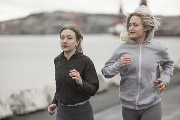 Two female runner friends running on dockside - CUF14276