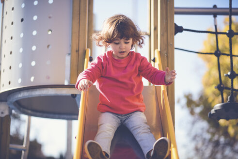 Porträt eines kleinen Mädchens auf einer Rutsche auf einem Spielplatz - JSMF00203