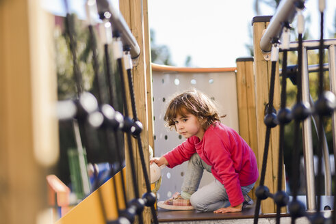 Porträt eines kleinen Mädchens auf einem Klettergerüst auf einem Spielplatz - JSMF00208