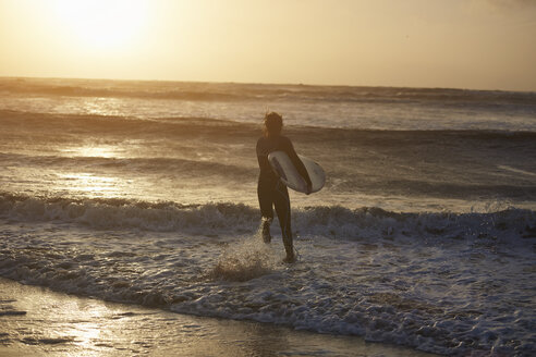 Junger männlicher Surfer mit Surfbrett läuft ins Meer, Devon, England, UK - CUF14336