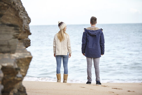 Rear view of young couple looking out from beach, Constantine Bay, Cornwall, UK - CUF14340
