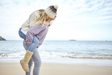 Junger Mann nimmt seine Freundin am Strand huckepack, Constantine Bay, Cornwall, UK - CUF14343